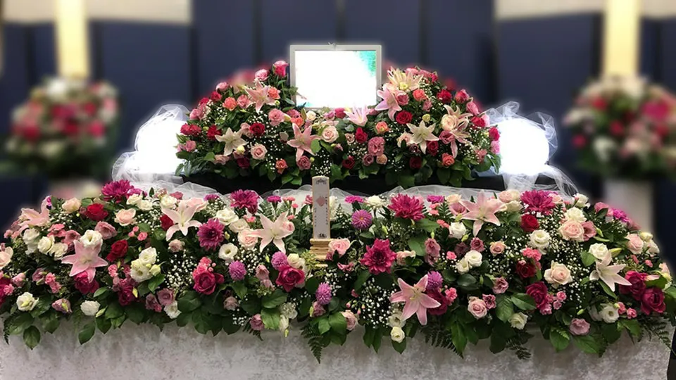 赤とピンクのバラやユリなどを使った、しっかり家族葬の生花祭壇